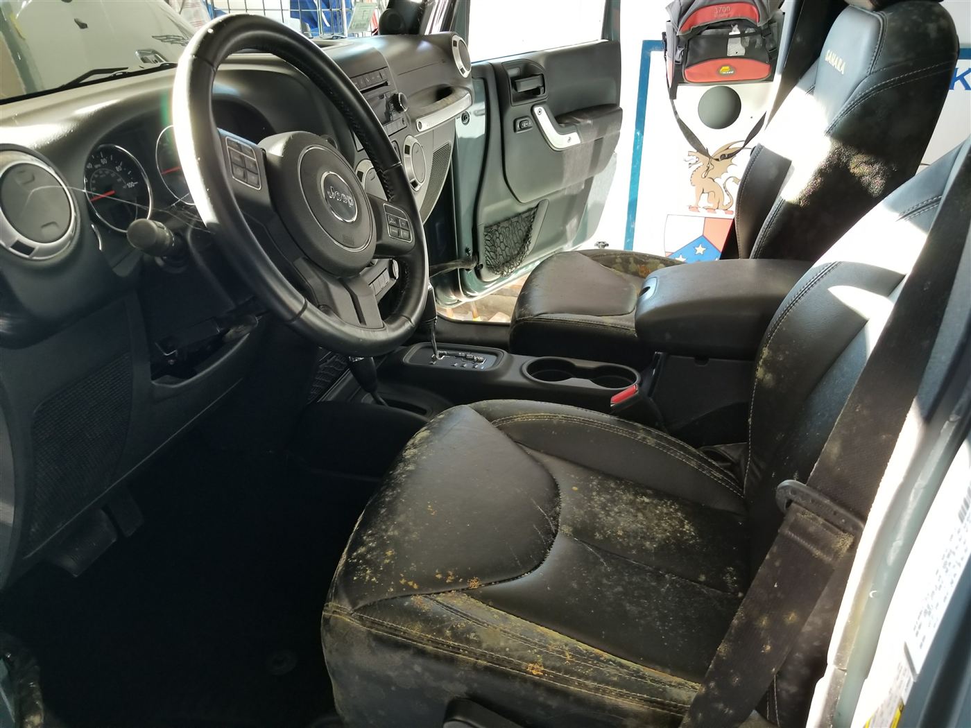 Before — mold colonies covering the leather seats and armrest of a Jeep interior