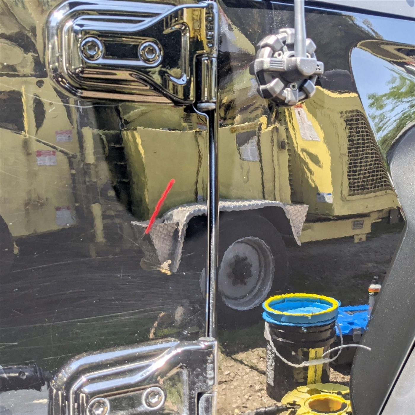 Paint correction in progress — half polished, half swirled black paint