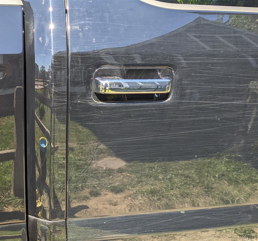 Deep scratches dragged across a black truck door — the kind Level 2 correction removes