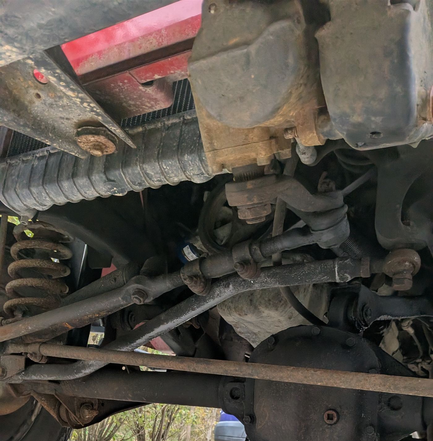 Before — surface rust spreading across tie rods, springs, and axle