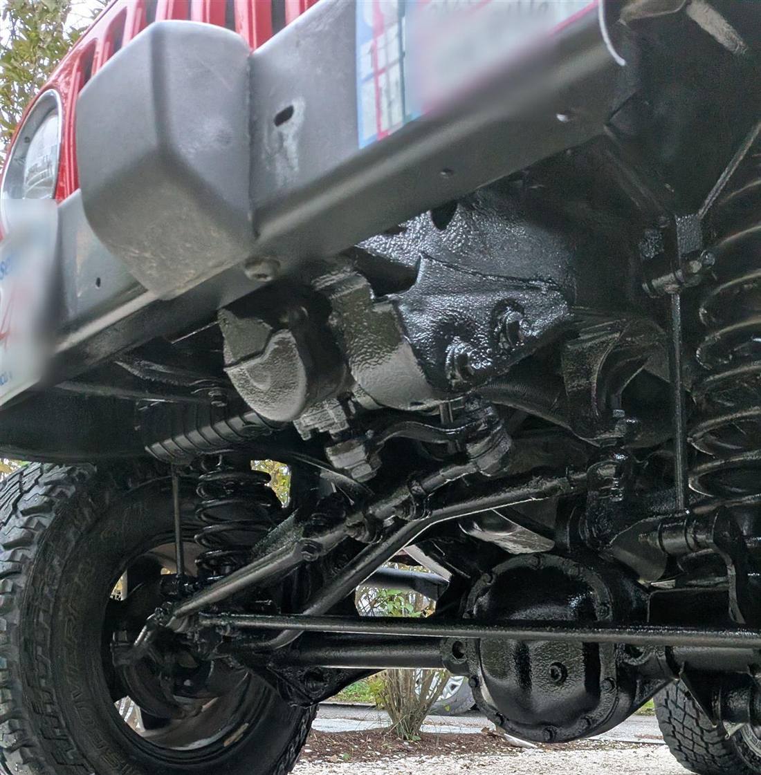 Fresh black FLUID FILM undercoating across a Jeep chassis and axles